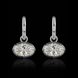 A pair of white gold huggie drop earrings with oval lab grown diamonds in a georgian setting with black rhodium.