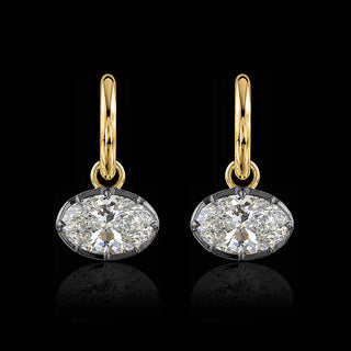 A pair of yellow gold huggie drop earrings with oval lab grown diamonds in a georgian setting with black rhodium.