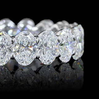 Close-up of oval lab grown diamond eternity band in 14k white gold, with 30-pointer diamonds in claw prong setting, 5 carats total.