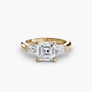 Three stone engagement ring setting in yellow gold, featuring an asscher-cut lab grown center diamond with tapered baguette side stones. || #metal_yellow gold #diamond shape_asscher
