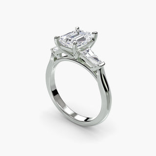 Three stone engagement ring setting in white gold with an emerald-cut lab grown center diamond and tapered baguette side stones, three-quarter view. || #metal_white gold|platinum #diamond shape_emerald
