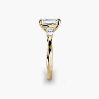 Three stone engagement ring setting in yellow gold showing the band profile, with an emerald-cut lab grown center diamond and tapered baguette side stones. || #metal_yellow gold #diamond shape_emerald