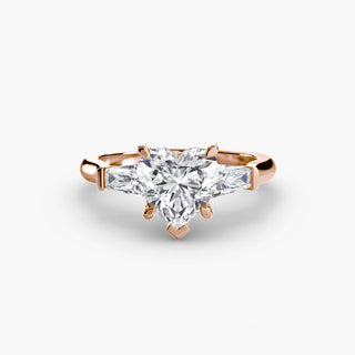 Three stone engagement ring setting in rose gold, featuring a heart-shaped lab grown center diamond with tapered baguette side stones. || #metal_rose gold #diamond shape_heart