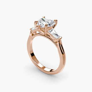 Three stone engagement ring setting in rose gold with a heart-shaped lab grown center diamond and tapered baguette side stones, three-quarter view. || #metal_rose gold #diamond shape_heart