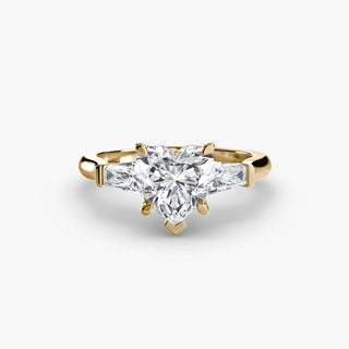 Three stone engagement ring setting in yellow gold, featuring a heart-shaped lab grown center diamond with tapered baguette side stones. || #metal_yellow gold #diamond shape_heart