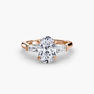 Three stone engagement ring setting in rose gold, featuring an oval-cut lab grown center diamond with tapered baguette side stones. || #metal_rose gold #diamond shape_oval