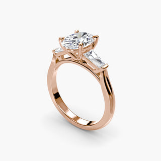 Three stone engagement ring setting in rose gold with an oval-cut lab grown center diamond and tapered baguette side stones, three-quarter view. || #metal_rose gold #diamond shape_oval