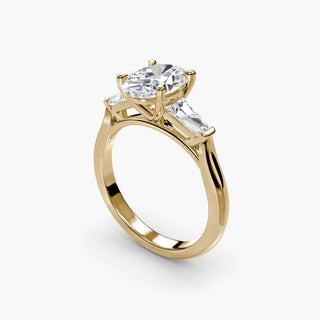 Three stone engagement ring setting in yellow gold with an oval-cut lab grown center diamond and tapered baguette side stones, three-quarter view. || #metal_yellow gold #diamond shape_oval