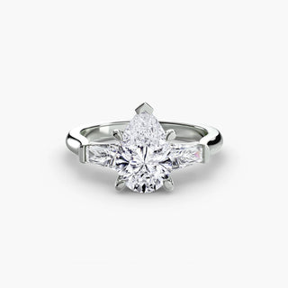 Three stone engagement ring setting in white gold, featuring a pear-shaped lab grown center diamond with tapered baguette side stones. || #metal_white gold|platinum #diamond shape_pear