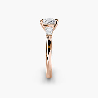 Three stone engagement ring setting in rose gold showing the band profile, with a princess-cut lab grown center diamond and tapered baguette side stones. || #metal_rose gold #diamond shape_princess