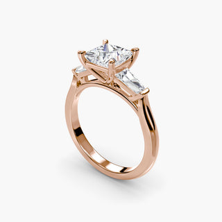 Three stone engagement ring setting in rose gold with a princess-cut lab grown center diamond and tapered baguette side stones, three-quarter view. || #metal_rose gold #diamond shape_princess