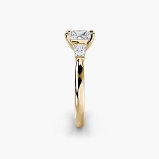 Three stone engagement ring setting in yellow gold showing the band profile, with a princess-cut lab grown center diamond and tapered baguette side stones. || #metal_yellow gold #diamond shape_princess