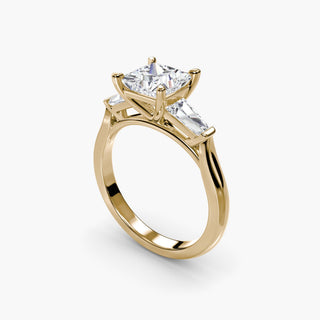 Three stone engagement ring setting in yellow gold with a princess-cut lab grown center diamond and tapered baguette side stones, three-quarter view. || #metal_yellow gold #diamond shape_princess