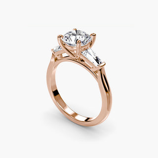 Three stone engagement ring setting in rose gold with a round lab grown center diamond and tapered baguette side stones, three-quarter view. || #metal_rose gold #diamond shape_round