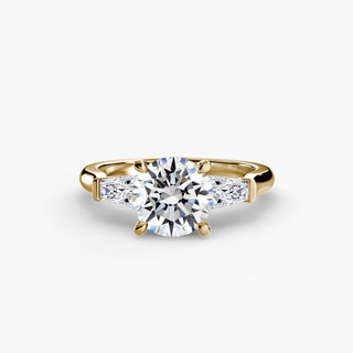 Three stone engagement ring setting in yellow gold, featuring a round lab grown center diamond with tapered baguette side stones. || #metal_yellow gold #diamond shape_round