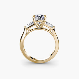 Three stone engagement ring setting in yellow gold, side profile view with a round lab grown center diamond and tapered baguette side stones. || #metal_yellow gold #diamond shape_round