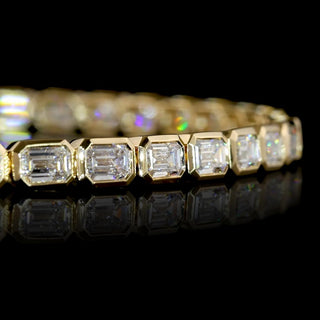 Close-up of East-West Emerald-cut lab grown diamond tennis bracelet in 14k yellow gold bezel setting.