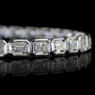 Close-up of East-West Emerald-cut lab grown diamond tennis bracelet in 14k white gold bezel setting.