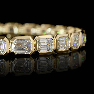 Close-up of East-West Emerald-cut lab grown diamond tennis bracelet, with 36-pointer diamonds in 14k yellow gold bezel setting, 10 carat total weight.