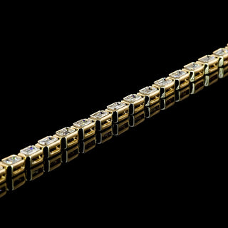 Lab-grown diamond tennis bracelet with emerald-cut diamonds in a yellow gold bezel setting, 7-inch length, 3 carats total weight.