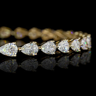 Close-up of East-west pear shaped lab grown diamond tennis bracelet, with 10 to 12-pointer pear diamonds in 14k yellow gold prong setting, 4 carats total. 