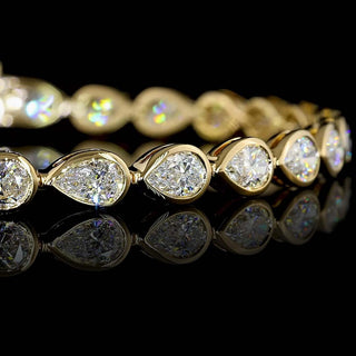 Close-up of East-West Pear-shaped lab grown diamond tennis bracelet, with 20-pointer pear diamonds in 14k yellow gold bezel setting, 6 carats total.