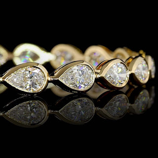 Close-up  East-West Pear-shaped lab grown diamond tennis bracelet, with 50-pointer (half carat each) pear diamonds in 14k yellow gold bezel setting.