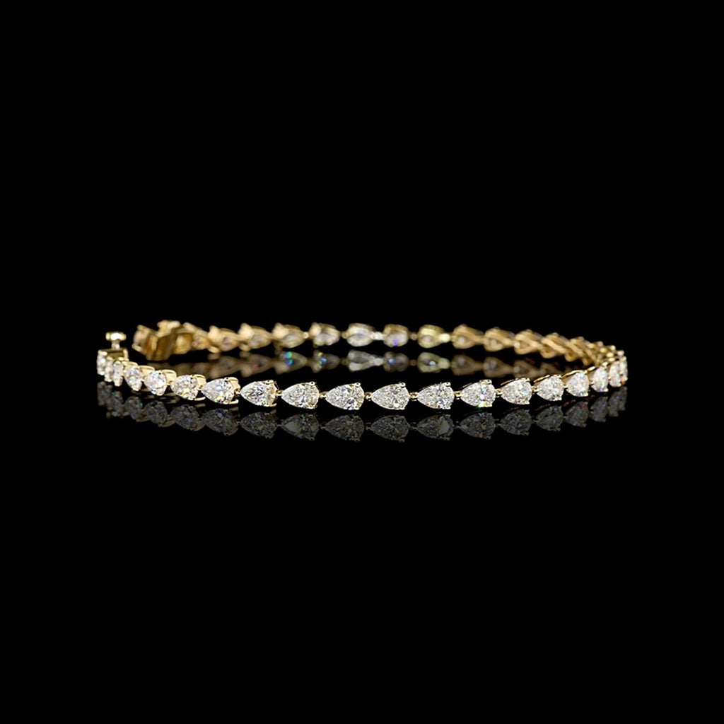 Video of east-west pear shaped lab grown diamond tennis bracelet in 14k yellow gold prong setting, 4 carats total. 